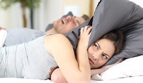 man snoring next to woman